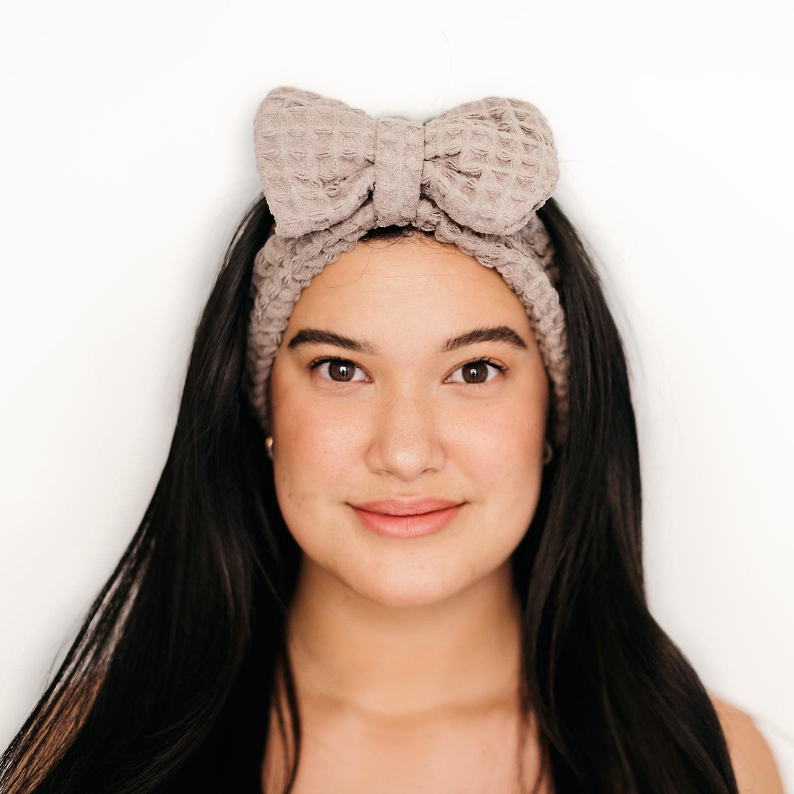 Woman with a bow spa headband, from Pomme Salon Canada, smiling at the camera.