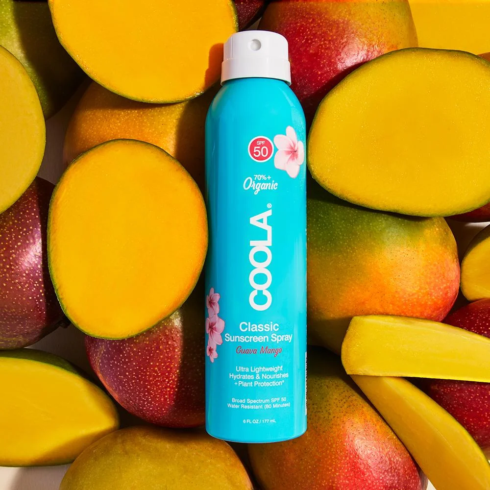 an image of the guava mango spray on sunscreen bottle ontop of half cut open mangoes.