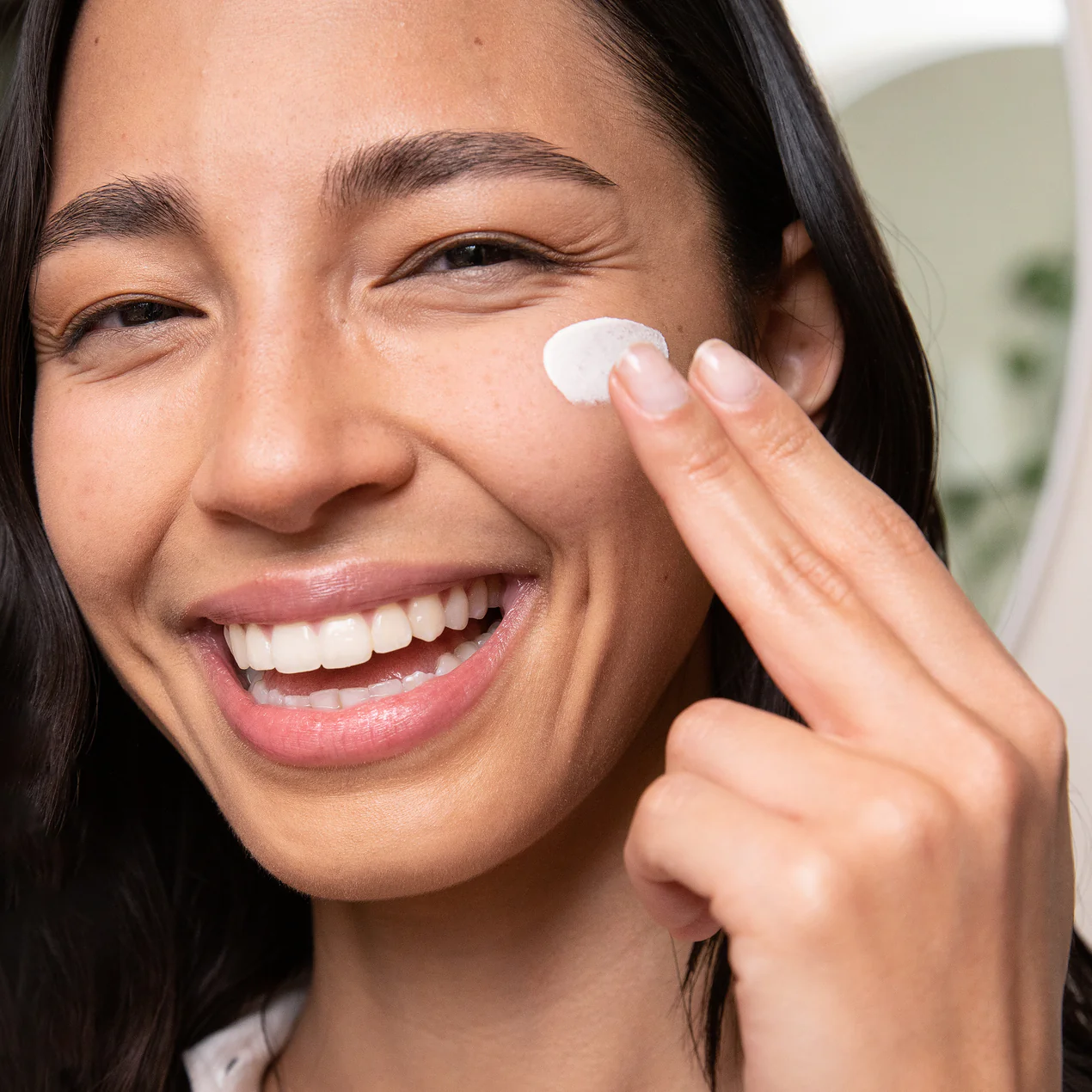 an image of a smiling model spreading the coola dew good product on their face